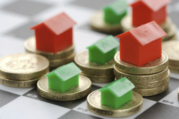 Plastic houses on top of pound coins on a chessboard. Primmer Olds B.A.S.